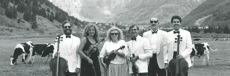 TCM in its early years — musicians in white tuxedos with their instruments, in a pasture below the Box Canyon